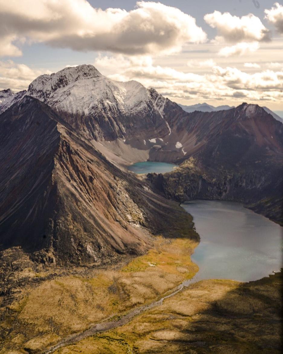 Two bright teal lakes in the bowl of a large mountain.