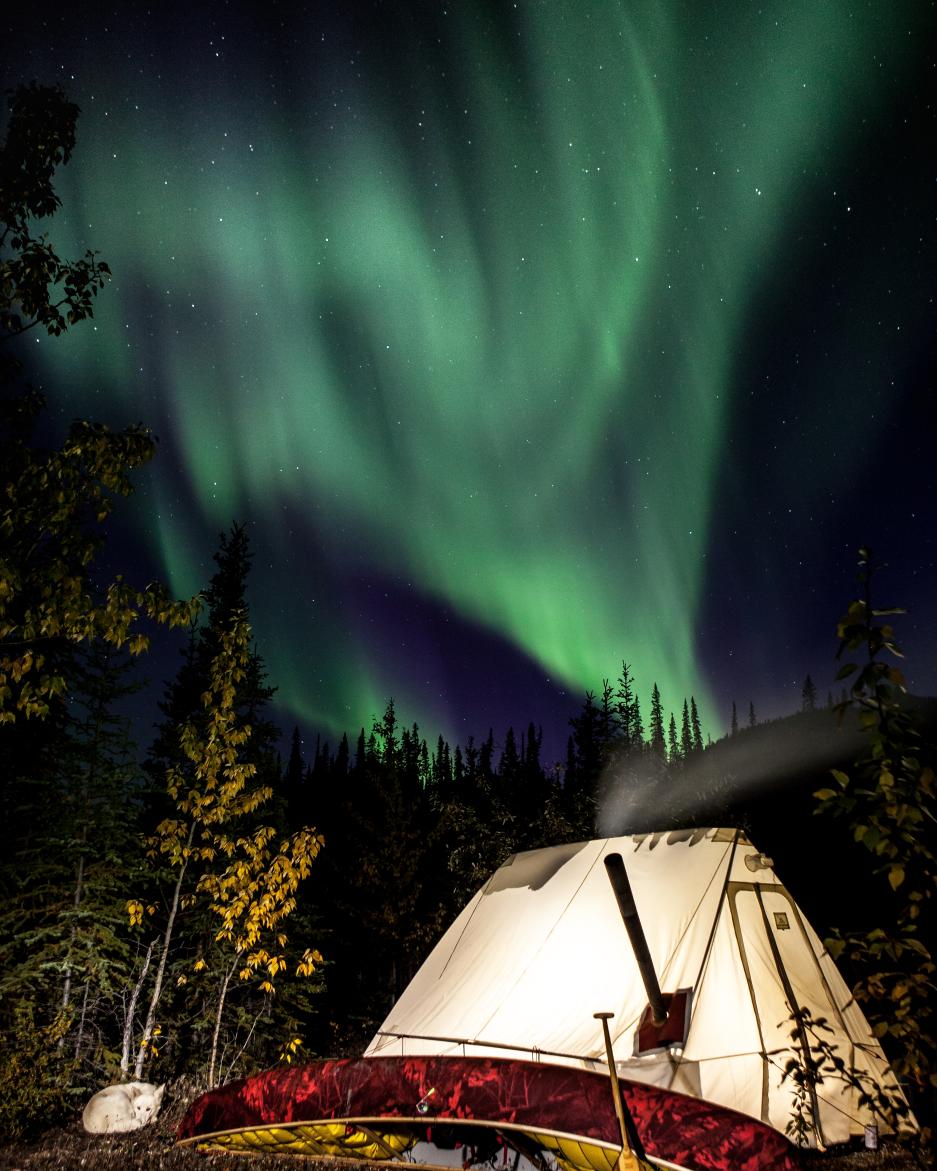 Aurora shines over a lit up wall tent