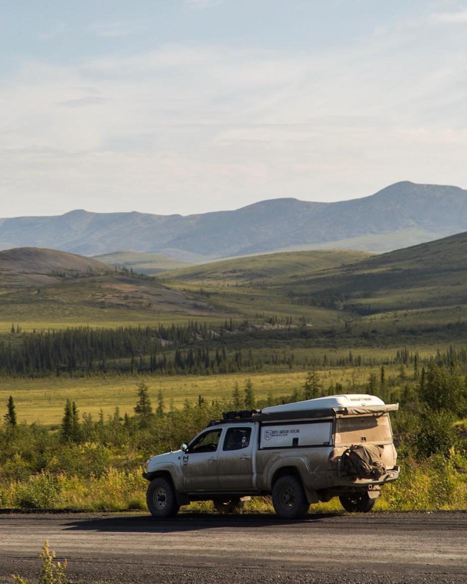 A truck is pulled over on the side of the road. Soft, green hills roll in the background