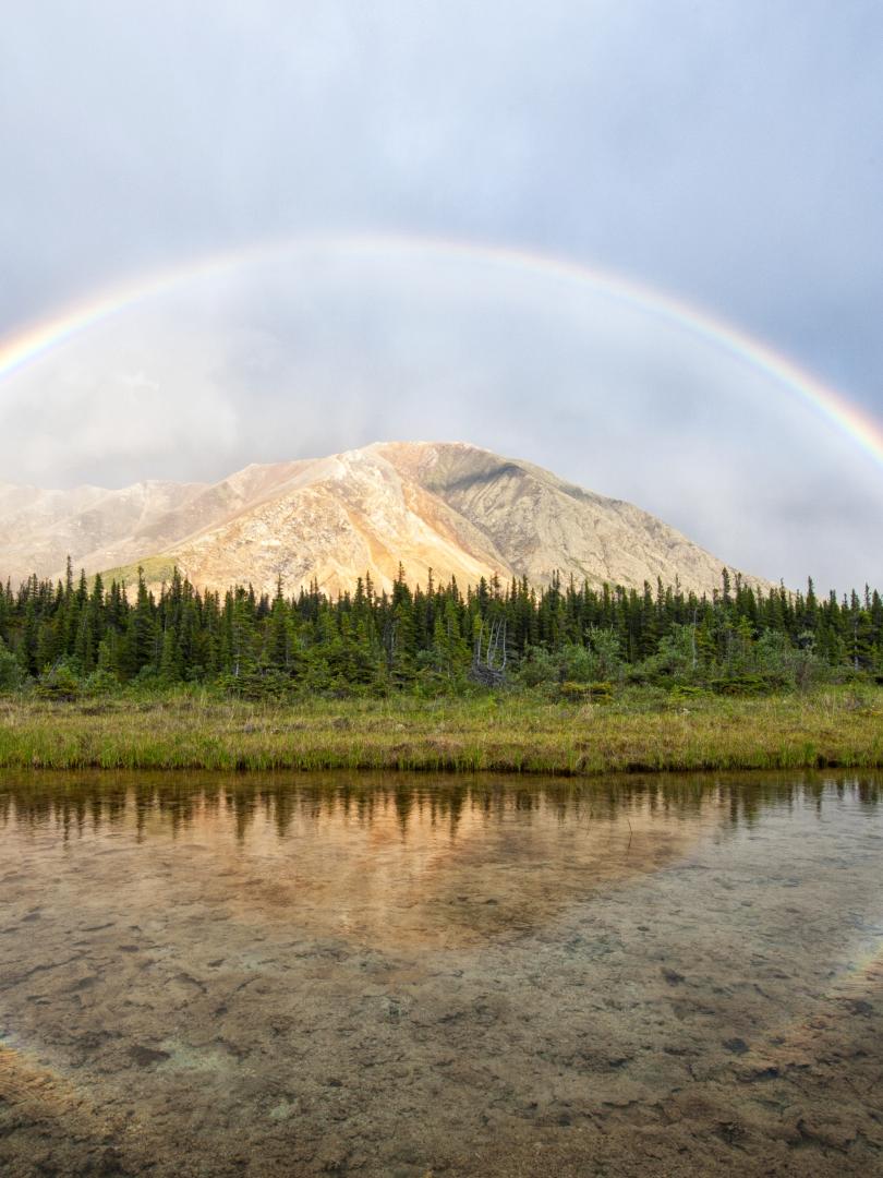 A rainbow stretches over a mountain