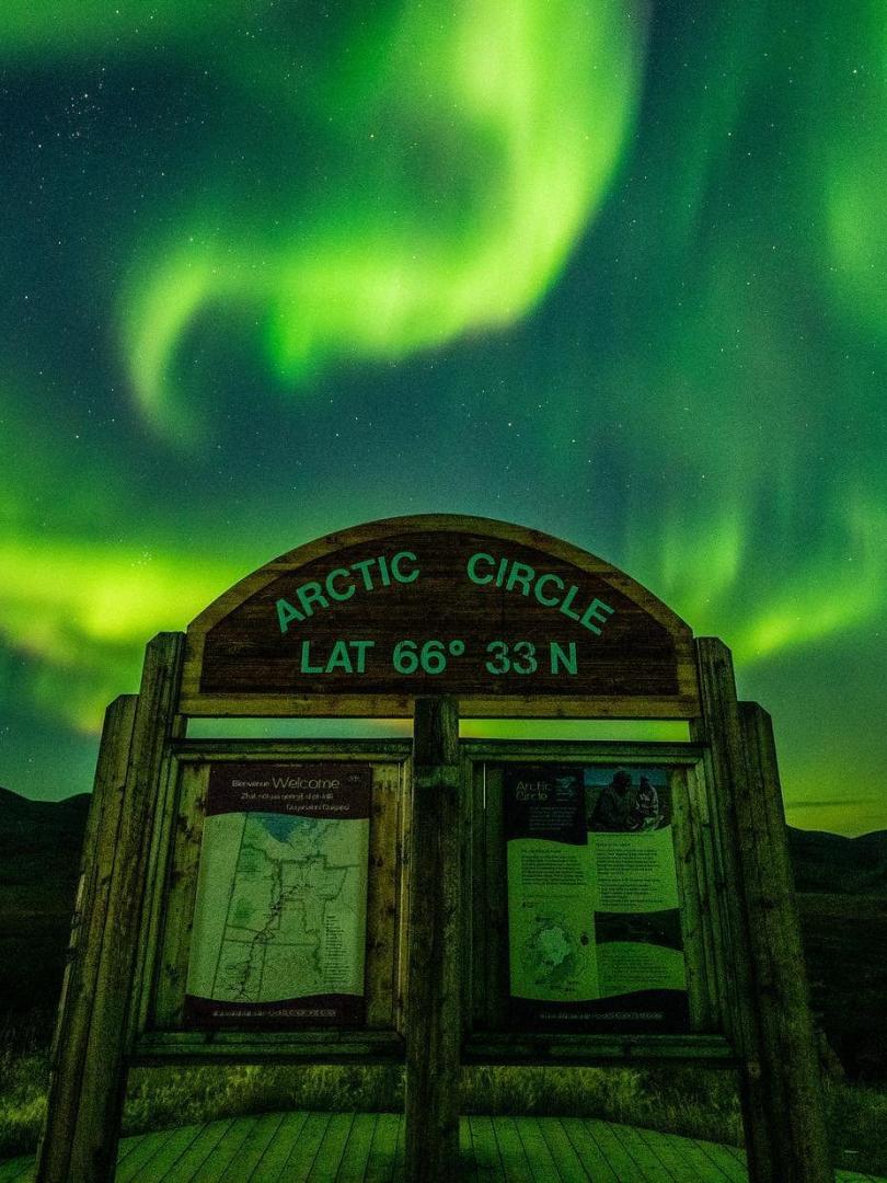 Arctic circle sign under northern lights