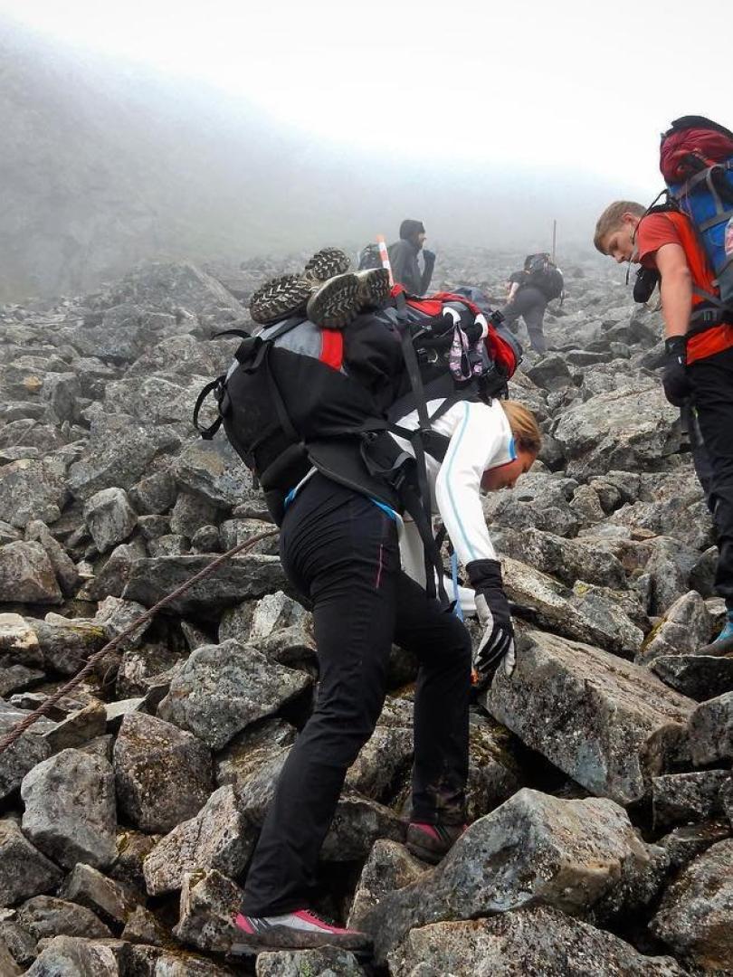 Two people navigate loose rocks on a hike