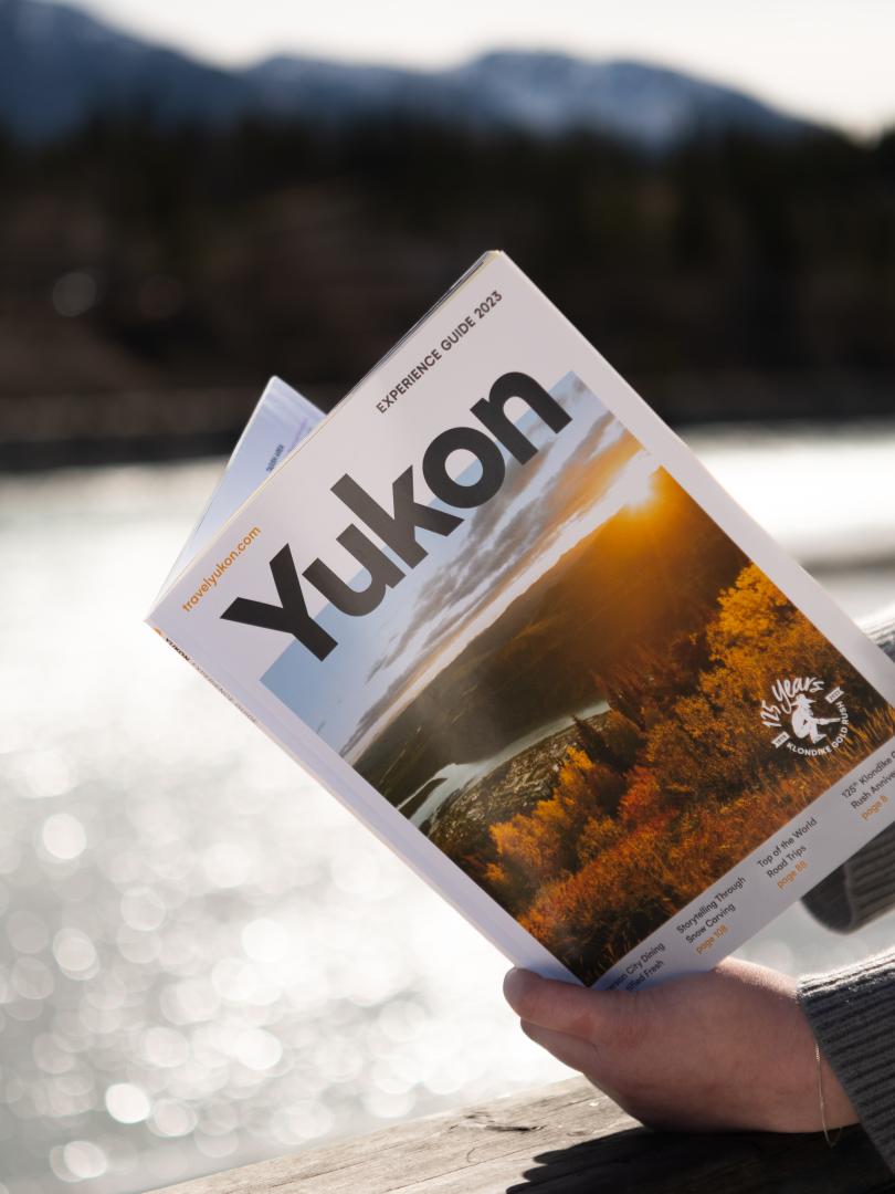A person reads the experience guide by the river