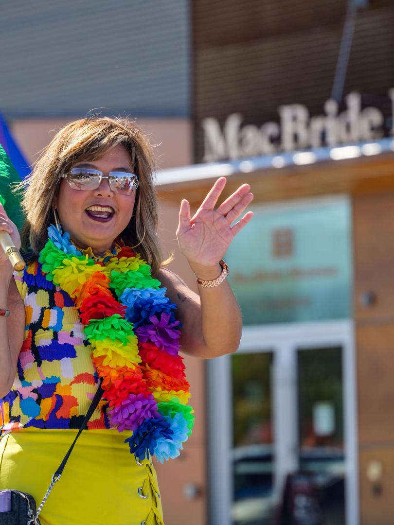 A woman wearing a rainbow necklace walking in a pride parade