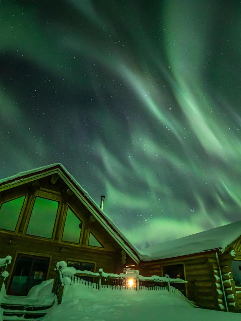 Aurora shines over the cabins at Northern Lights Resort and Spa