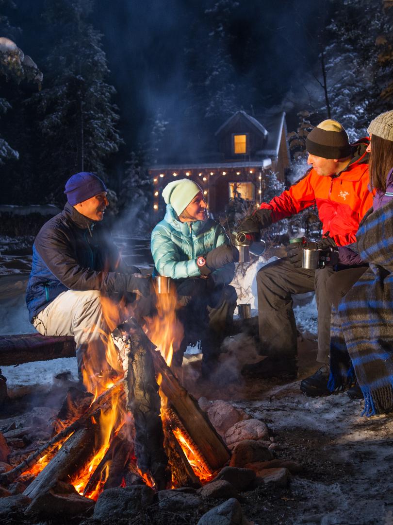 Group gathering around a fire with hot chocolate 