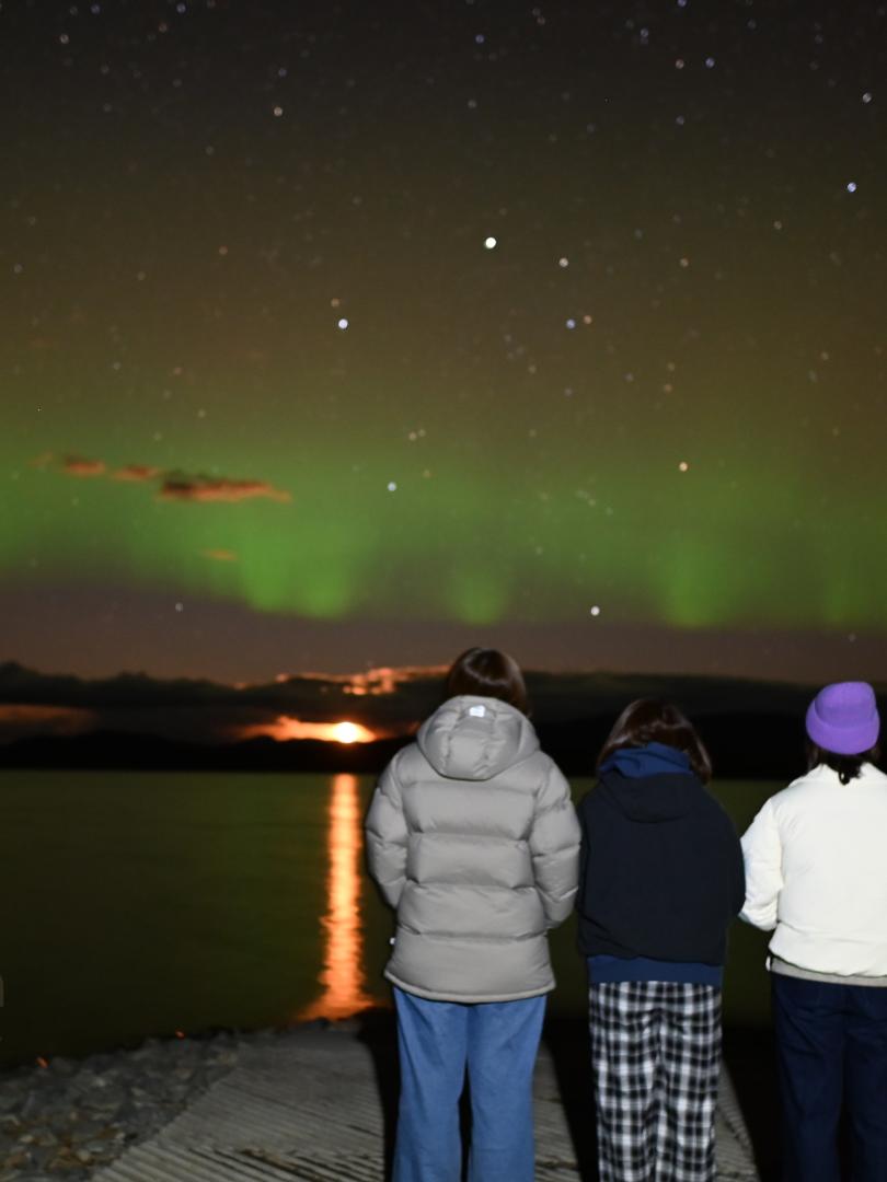 Northern lights on a lake with four guests