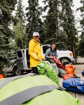 Two people packing their bags for a canoeing trip.