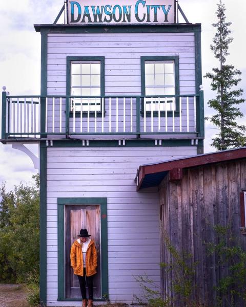 A woman standing in front of the purple Dawson City sign