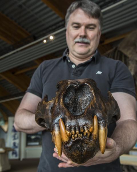 A man holds a dark brown fossilized head