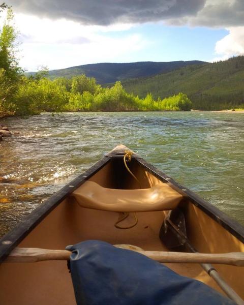 A canoe sits on the shores of a river under the sunshine