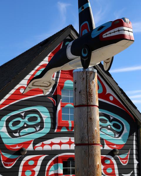 A totem pole and carcross tagish first nation mural on a small building
