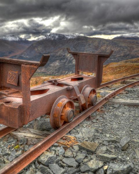 Old rusty mining equipment on railroad tracks