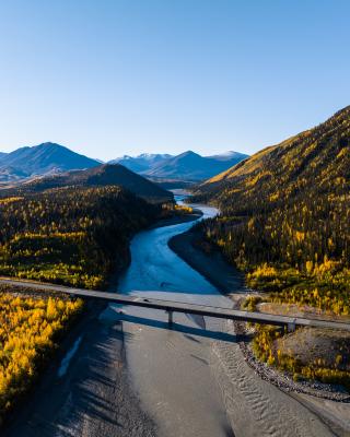 A river runs through a mountain valley. A bridge crosses the river.