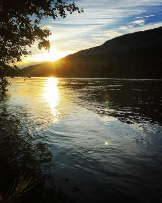 The sun sets over a mountain ridge, reflecting in a lake