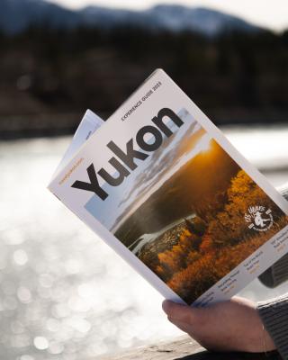 A person reads the experience guide by the river 
