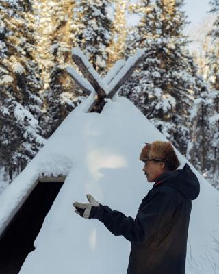 man standing outside a first nation hut