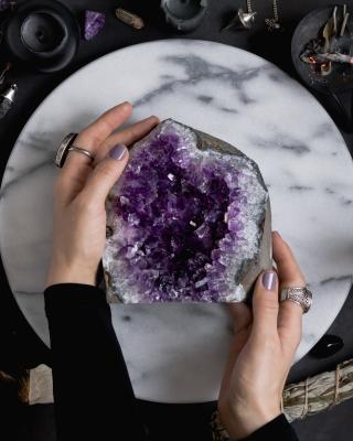 top view of women's hands holding large amethyst piece