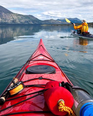 A red kayak on a lake with mountains in the distance 