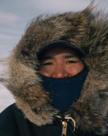 A man on a snowy tundra in a fur hooded parka