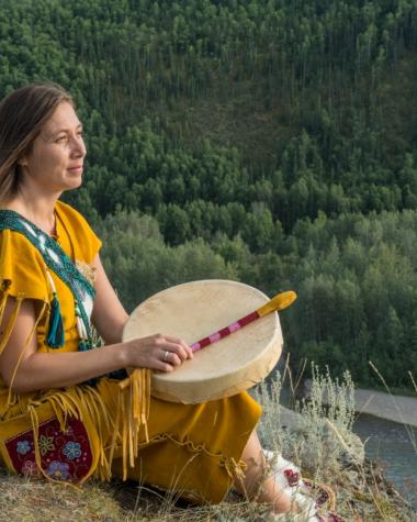 A Trondek Hwechin dancer overlooks a river