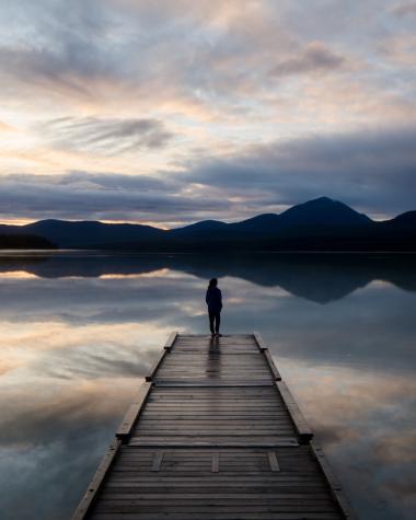 A person enjoys the sunset on the dock at Squaga Lake Campground