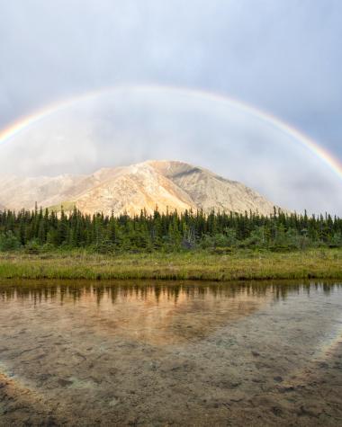 A rainbow stretches over a mountain