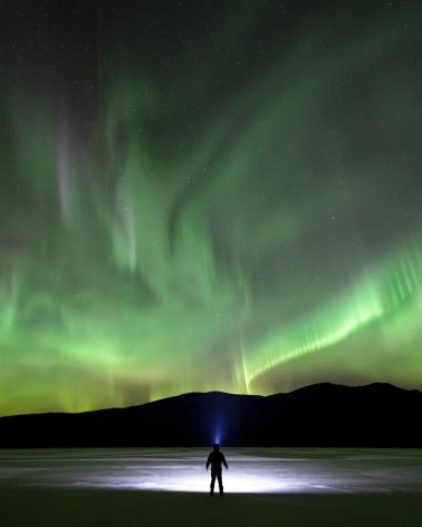 A person stands in awe under the northern lights