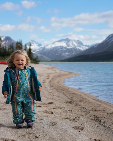 Little girl standing on shore of lake