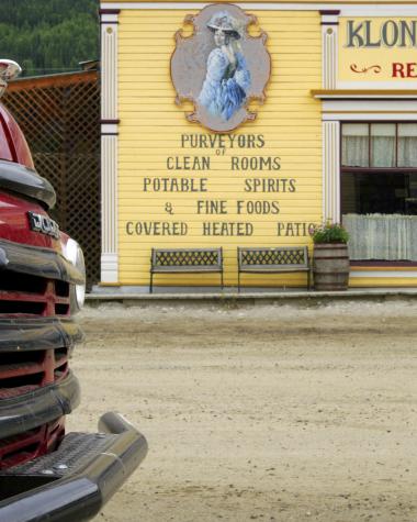 A retro red truck is parked outside a yellow vintage building