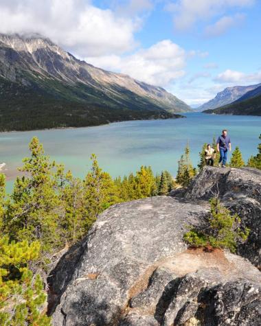Two people climb over large rocks on the Chilkoot trail