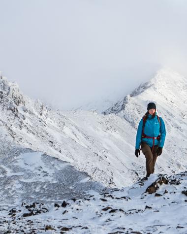 A woman walking along a snowy ridge