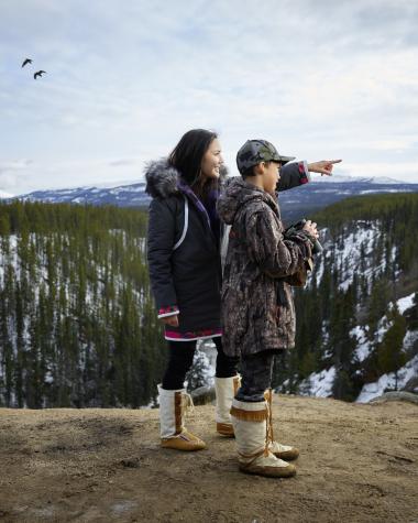 mom and son at a ridge look out with ravens flying overhead