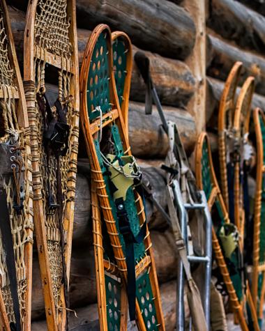 Snowshoes leaning against a log cabin