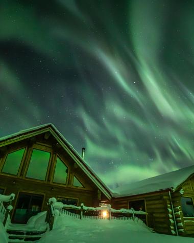 Aurora shines over the cabins at Northern Lights Resort and Spa