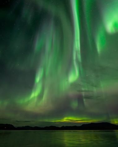 Northern lights shine over the open water