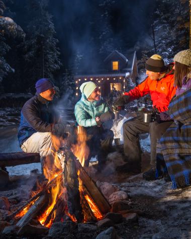 Group gathering around a fire with hot chocolate 