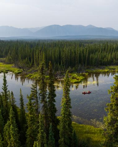 Canoeing on one of the many small lakes along the Campbell Highway near Ross River. The St. Cyr Range of the Pelly Mountains is in the hazy distance.