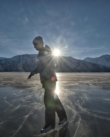 A person skates on a frozen lake on a clear sunny day